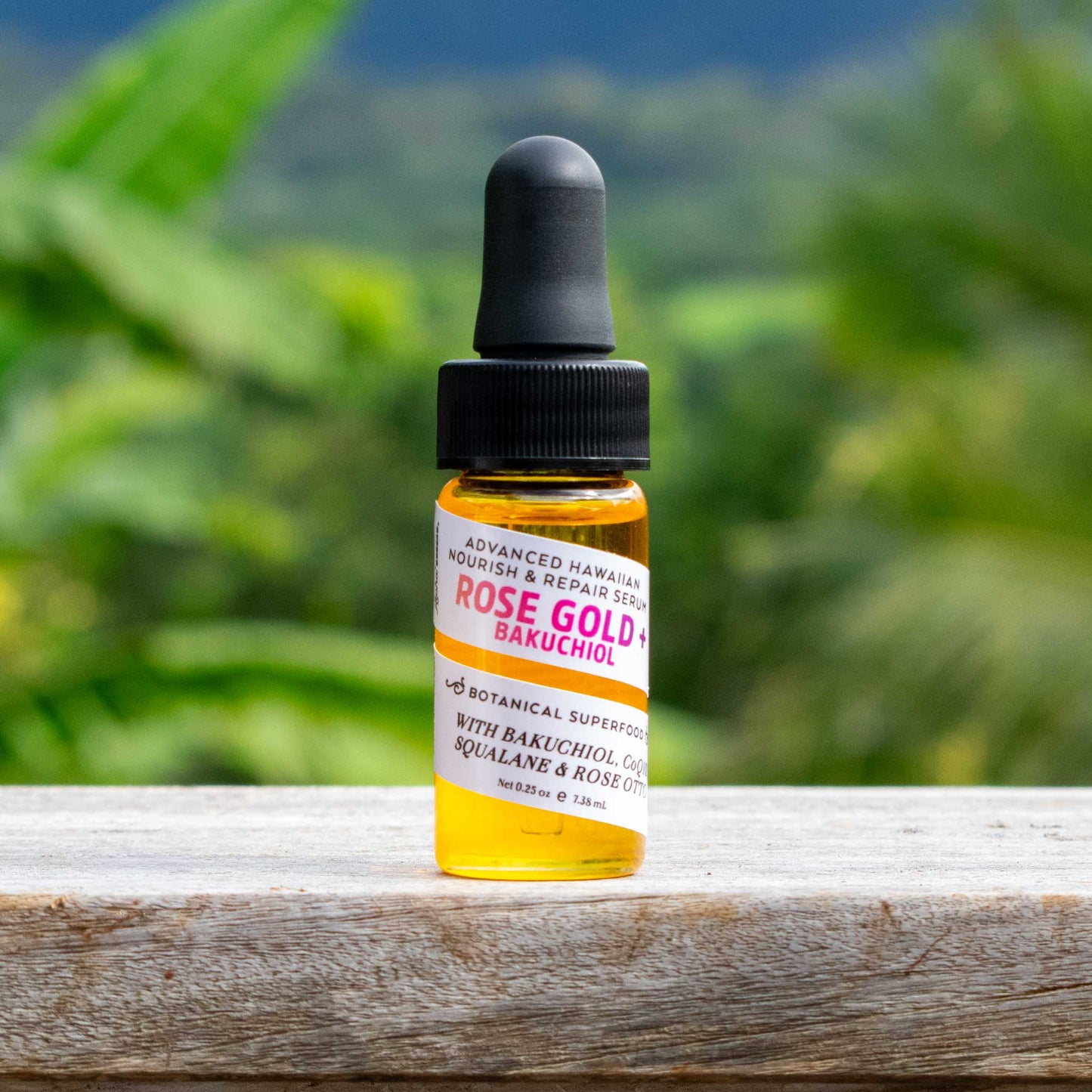 Rose Gold + Bakuchiol 0.25 oz serum bottle with soft focus Kaua'i forrest in the background